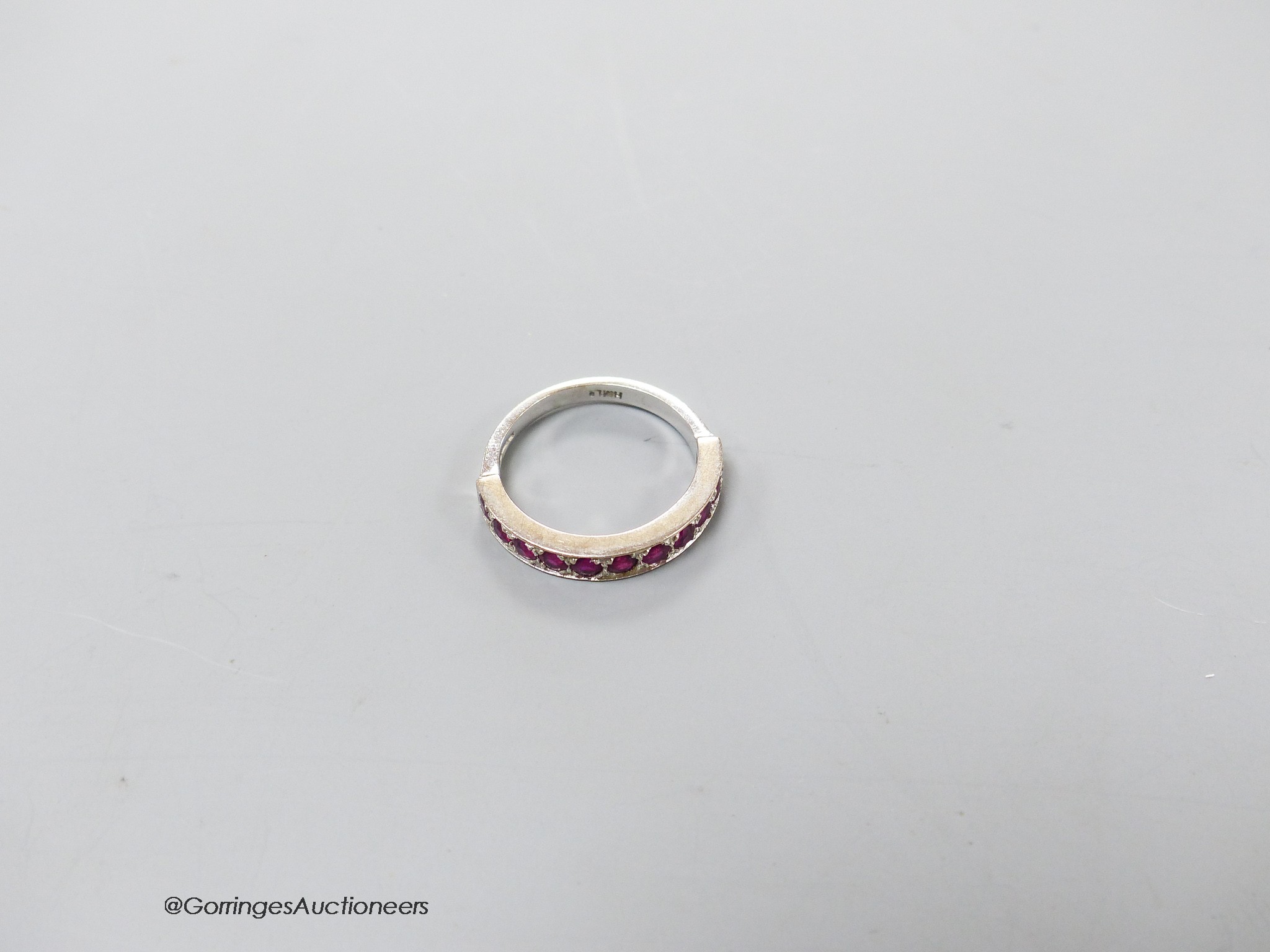 A modern 18ct white gold and eleven stone ruby set half eternity ring, size L, gross 3.7 grams.